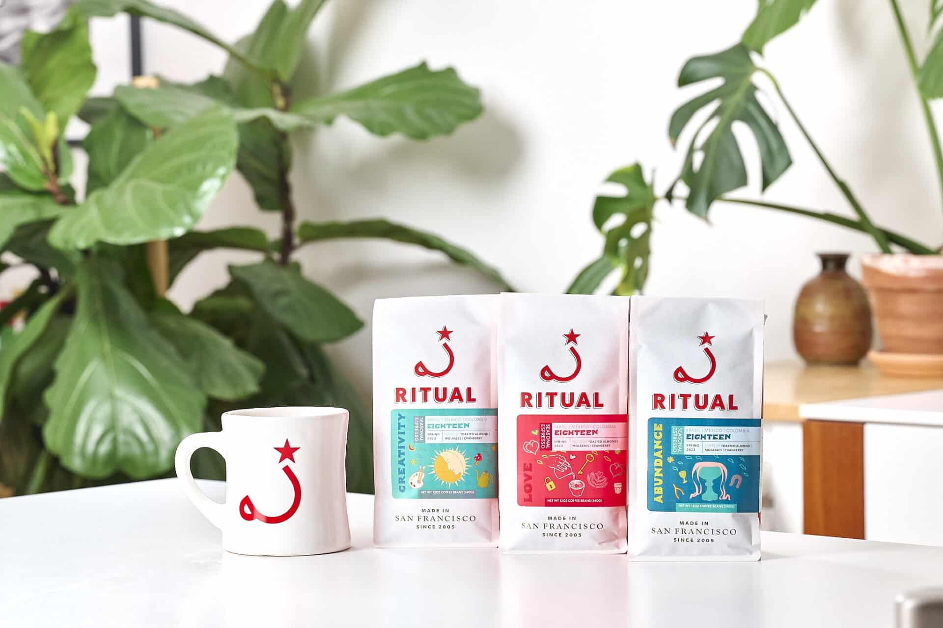 Mug and 3 espresso bags on table with plant in the background