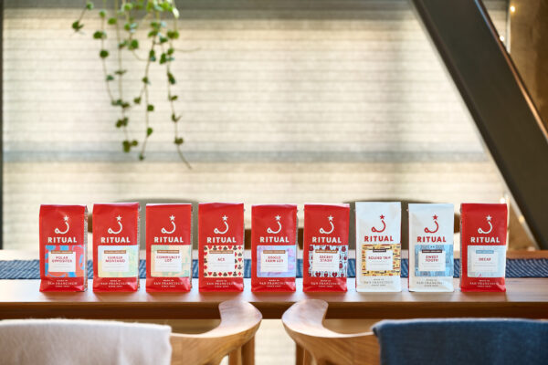 Nine 12 ounce bags of Ritual Coffee in a line on a wooden dining table
