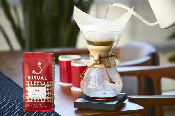 12oz bag of Ace Hacienda Carmona on a table with a kettle pouring water into a Chemex brewer on the right