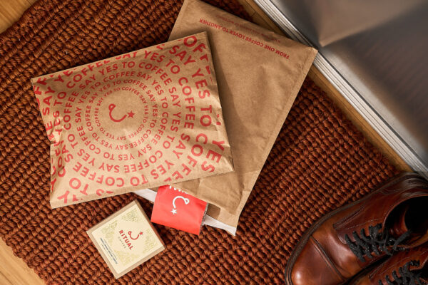 Mailers on top of each other with a 12oz bag of coffee and box of instant coffee