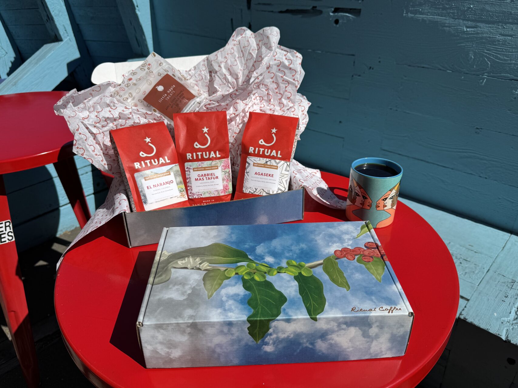 Three 10 ounce bags of coffee in a box on a red table