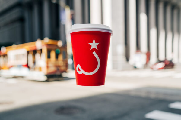 Ritual red to go cup floating in front of a cable car